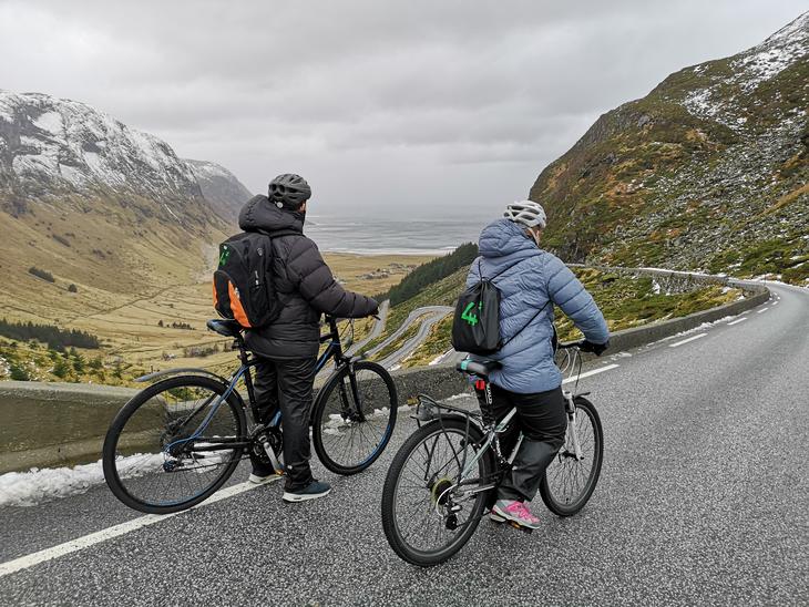 To ungdommer med 4H-sekk på ryggen sykler nedover en svingete vei, foto: Camilla Nesheim.
