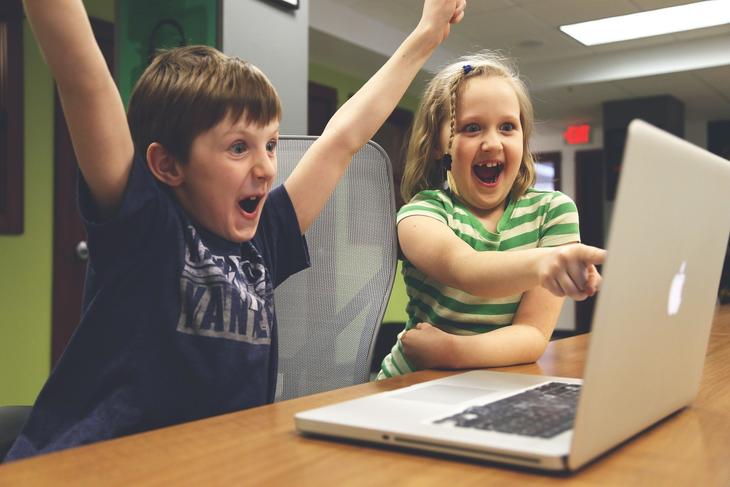 To barn som jubler bak datamaskin